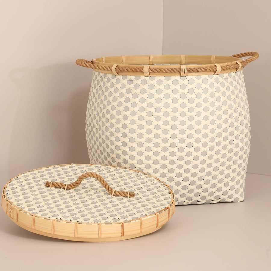 Woven laundry basket with lid, Decorative rope handle hamper, Bamboo rim woven storage basket, Beige and grey basket with lid, Handmade woven bin, Neutral tone woven basket for home organization, Eco-friendly hamper with bamboo details, Decorative storage basket for bedroom or living room, Woven basket with rope handles and lid.