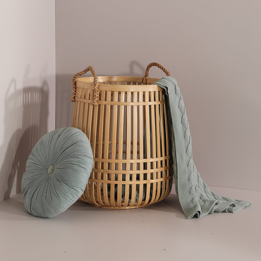 Japandi décor inspiration, Minimalist cozy corner, Boho neutral home styling, Knitted sage green throw, Soft woven blanket, Round tufted throw pillow, Velvet decorative cushion, Large bamboo laundry basket, Natural woven storage basket.