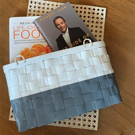 Hanging magazine basket, Two-tone woven wall organizer, Grey and white storage basket, Plastic strip woven magazine holder, Wall-mounted file holder, Handwoven wall pocket, Decorative magazine organizer, Vertical wall storage basket, Modern woven magazine rack, Woven hanging basket for books.