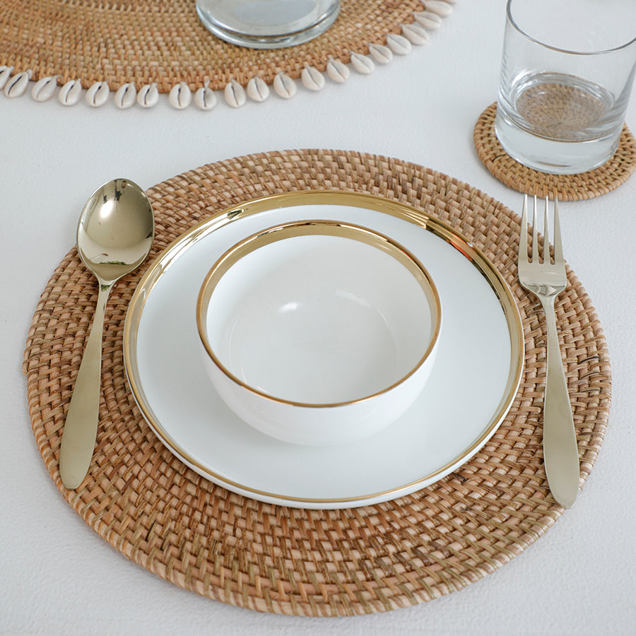 Natural rattan placemat, Handwoven wicker table mat, Round rattan dining placemat, Eco-friendly table setting mat, Rustic Boho placemat, White ceramic dinnerware set, Gold rim porcelain plate and bowl, Luxury white and gold crockery, Elegant ceramic dish set, Minimalist gold-trimmed dinnerware.