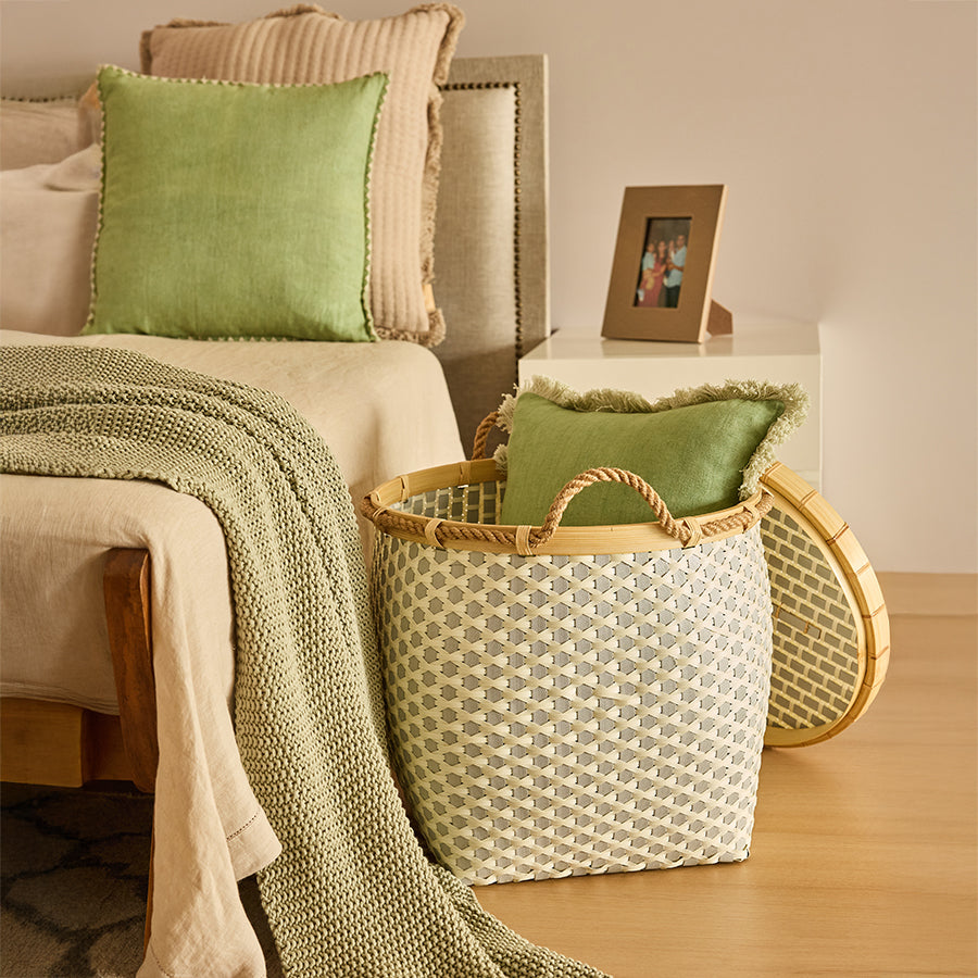 Bedroom woven storage basket, Decorative basket with lid and rope handles, Eco-friendly bedroom hamper, Handcrafted bedside basket, Wicker-style laundry basket, Natural woven basket for home décor, Multi-functional storage basket for bedroom, Soft green cushion with fringe, Knitted throw blanket for bed, Stylish room storage solution.