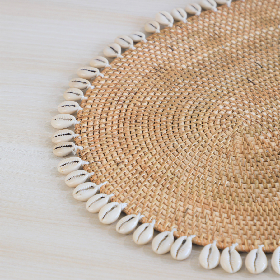 Cowrie shell placemat, Woven rattan placemat, Boho table mat, Natural straw placemat, Shell edge table décor, Handmade Boho placemat with shells, Coastal style dining table mat, Shell-trimmed jute placemat, Rustic woven placemat with cowries,
Eco-friendly beach themed table décor.