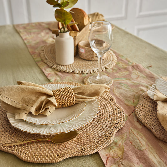 wavy rattan placemat, organic woven placemat, Boho charger plate, handcrafted rattan table mat, natural fiber table setting, embossed ceramic dinner plate, white scalloped edge plate, elegant ceramic dinnerware, classic white table plate, textured ceramic dish, beige linen napkin, natural cotton napkin, woven rattan napkin ring. 