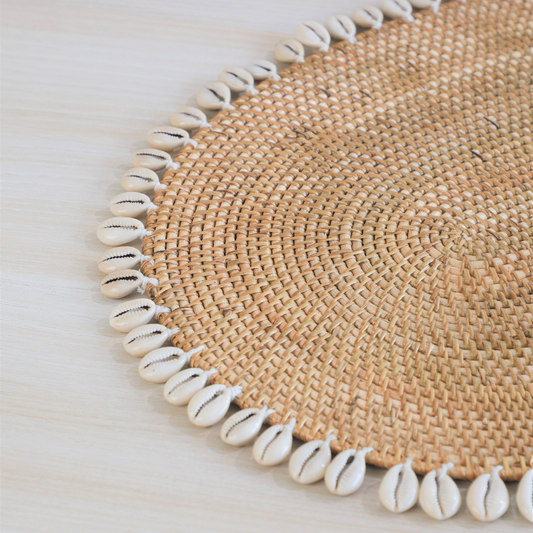 Cowrie shell placemat, Woven rattan placemat, Boho table mat, Natural straw placemat, Shell edge table décor, Handmade Boho placemat with shells, Coastal style dining table mat, Shell-trimmed jute placemat, Rustic woven placemat with cowries, 
Eco-friendly beach themed table décor. 


